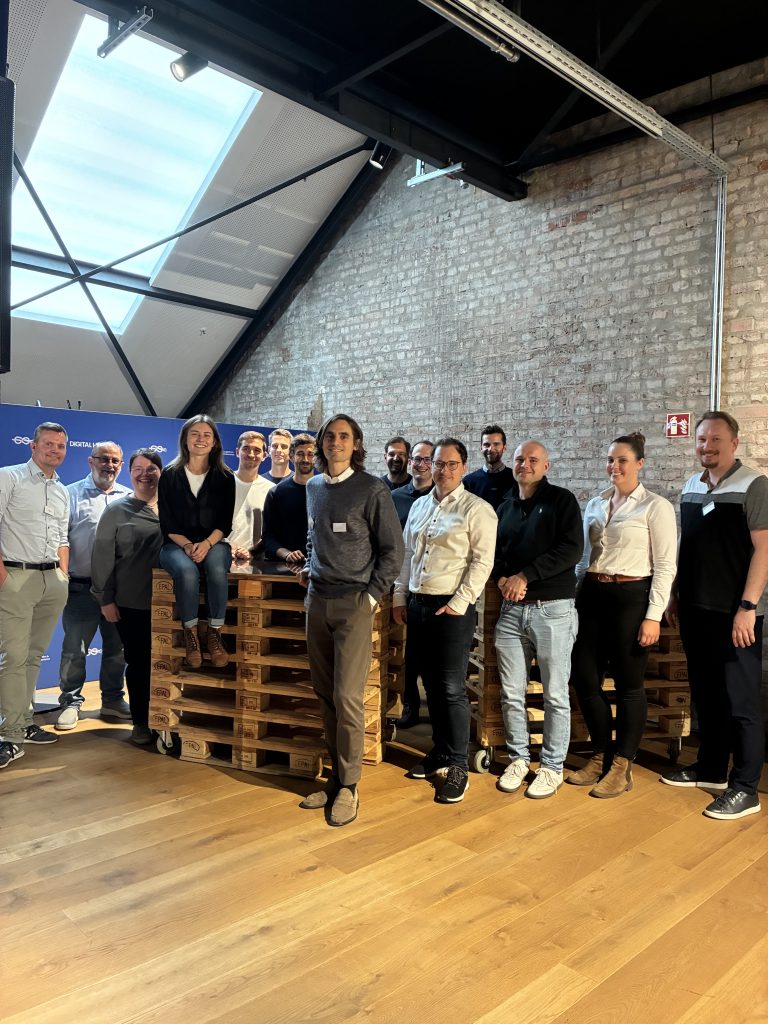 Gruppenbild von den Teilnehmenden am Konsortialtreffen auf einem Palettenstapel